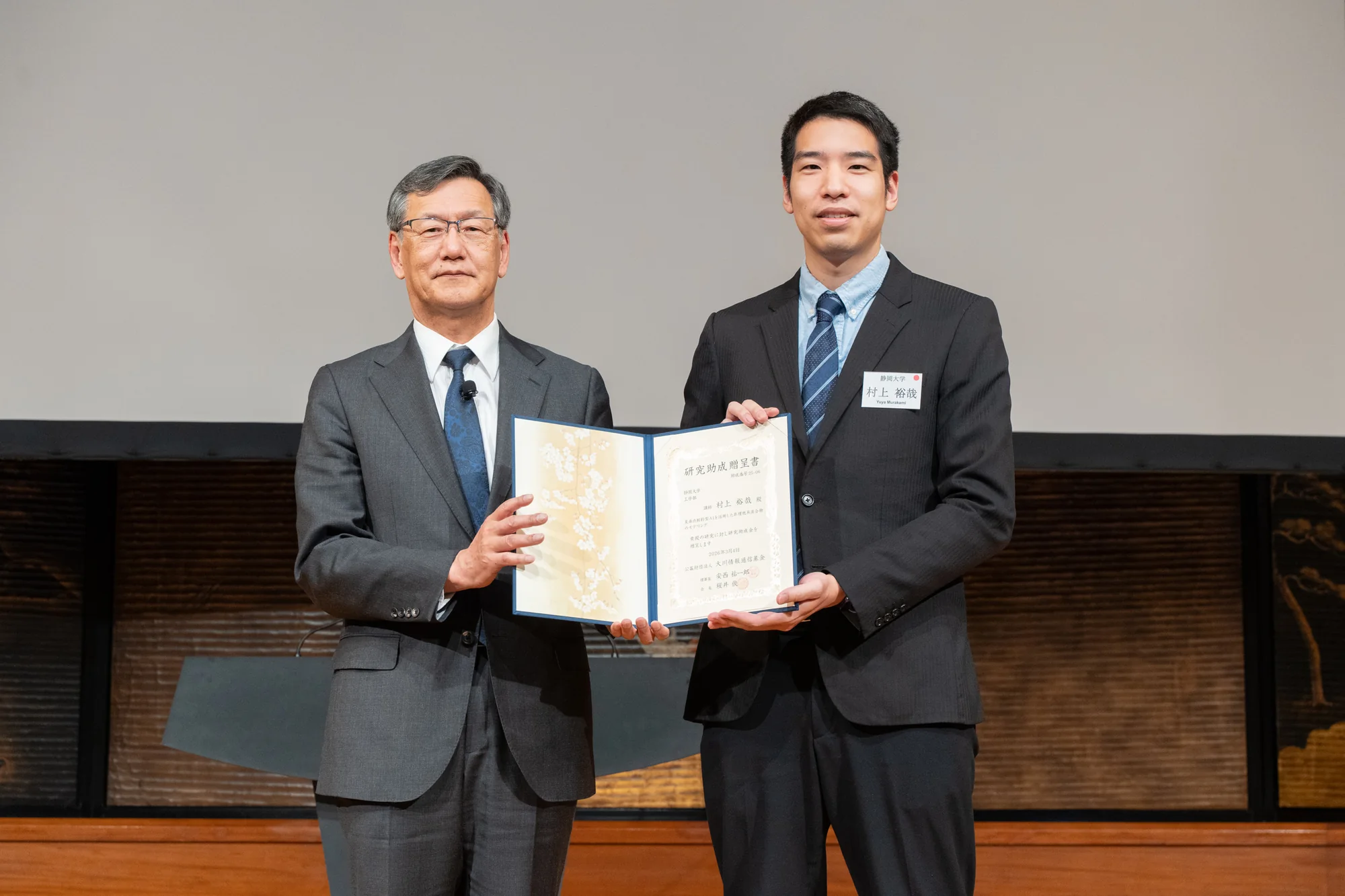 研究助成贈呈式で助成決定通知書を手にする村上裕哉准教授