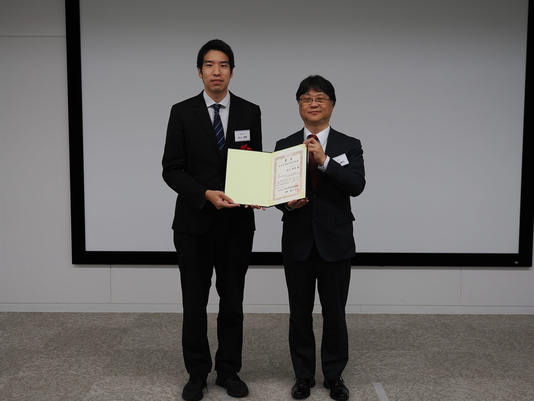 授賞式で賞状を手にする村上裕哉准教授