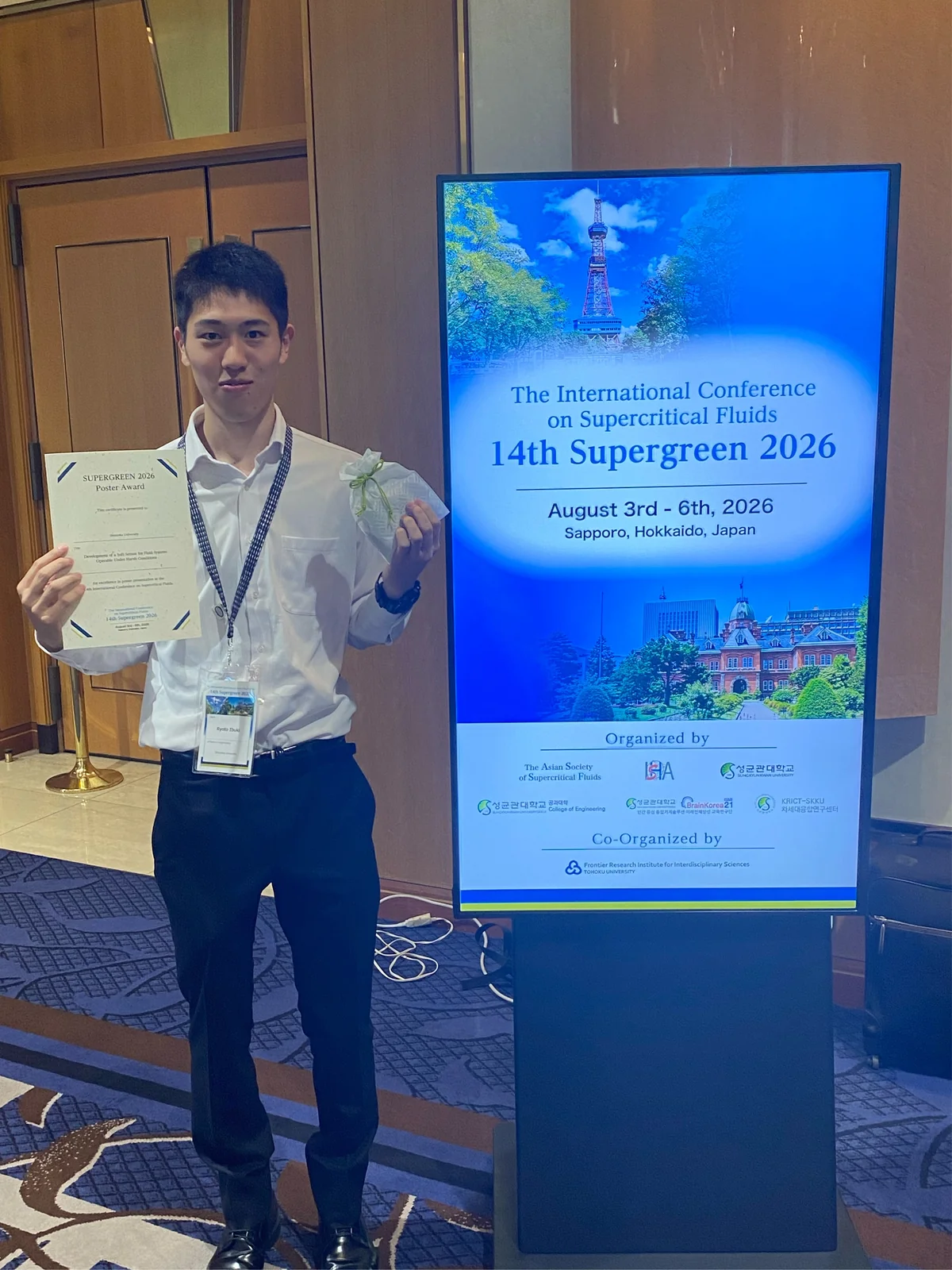 14th Supergreen 2026の会場でPoster Awardの賞状を持つ伊吹亮人